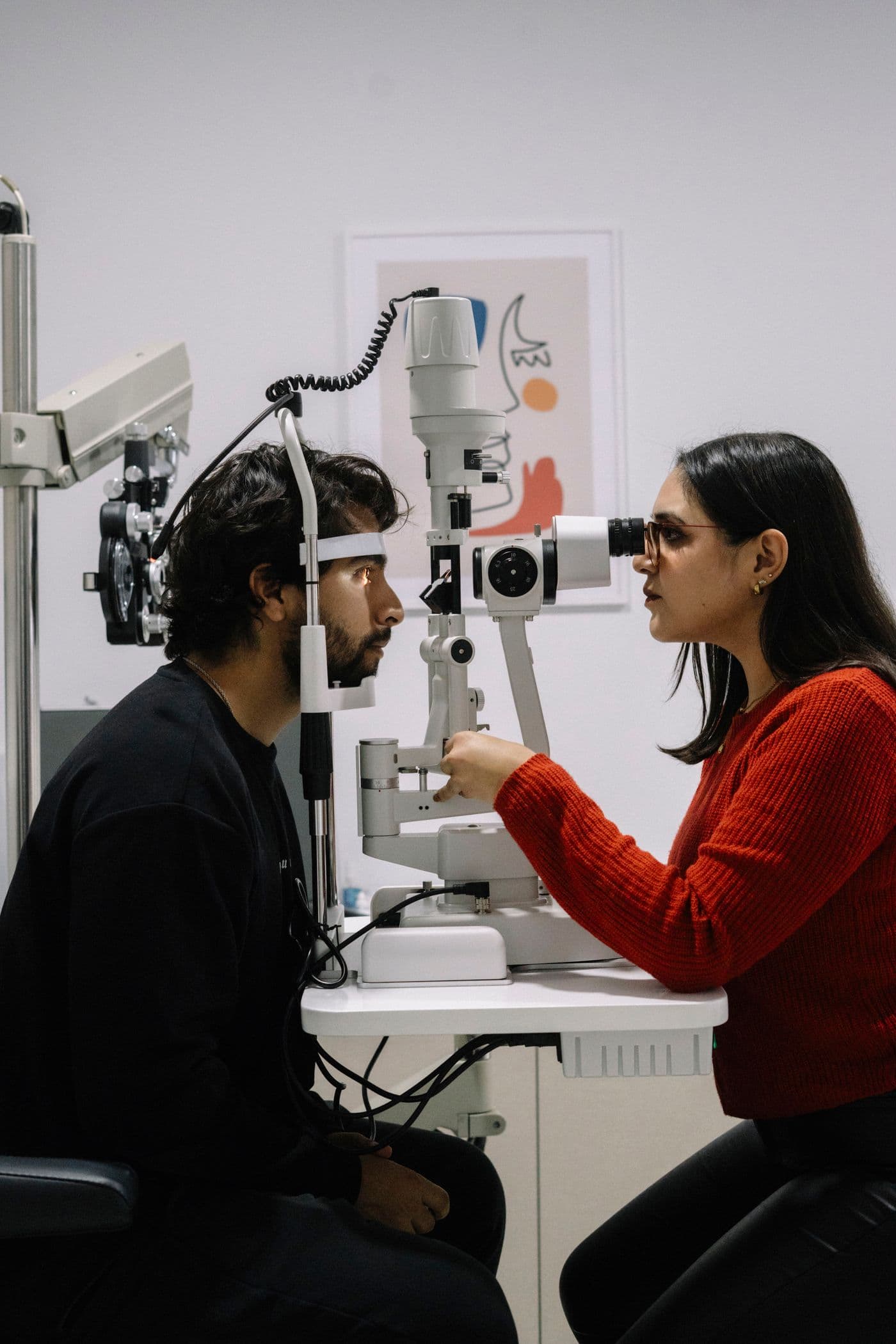 An ophthalmologist examining a patient at a slit lamp